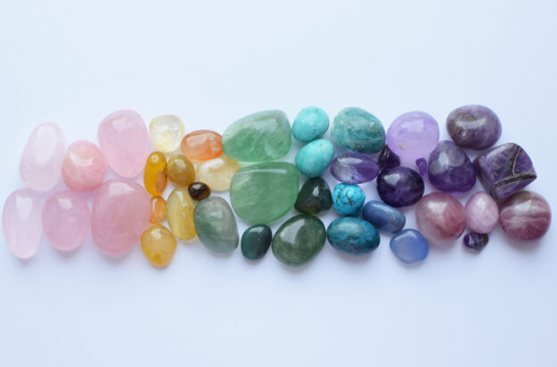 Multicolored healing chakra crystals. The stones are laid out in the shape of a rainbow. Real semi-precious stones: rose quartz, amethyst, citrine, agate, apatite, kyanite, fluorite.