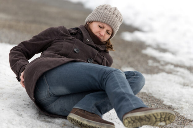 young woman has an accident on a icy way with black ice