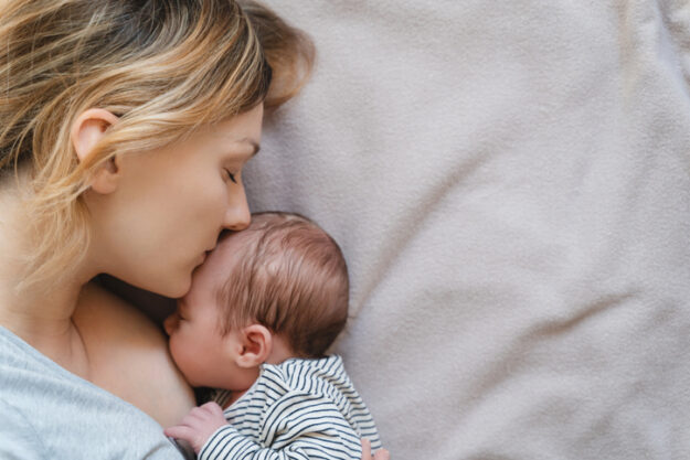 Mother breastfeeding baby. Baby eating mother’s milk.